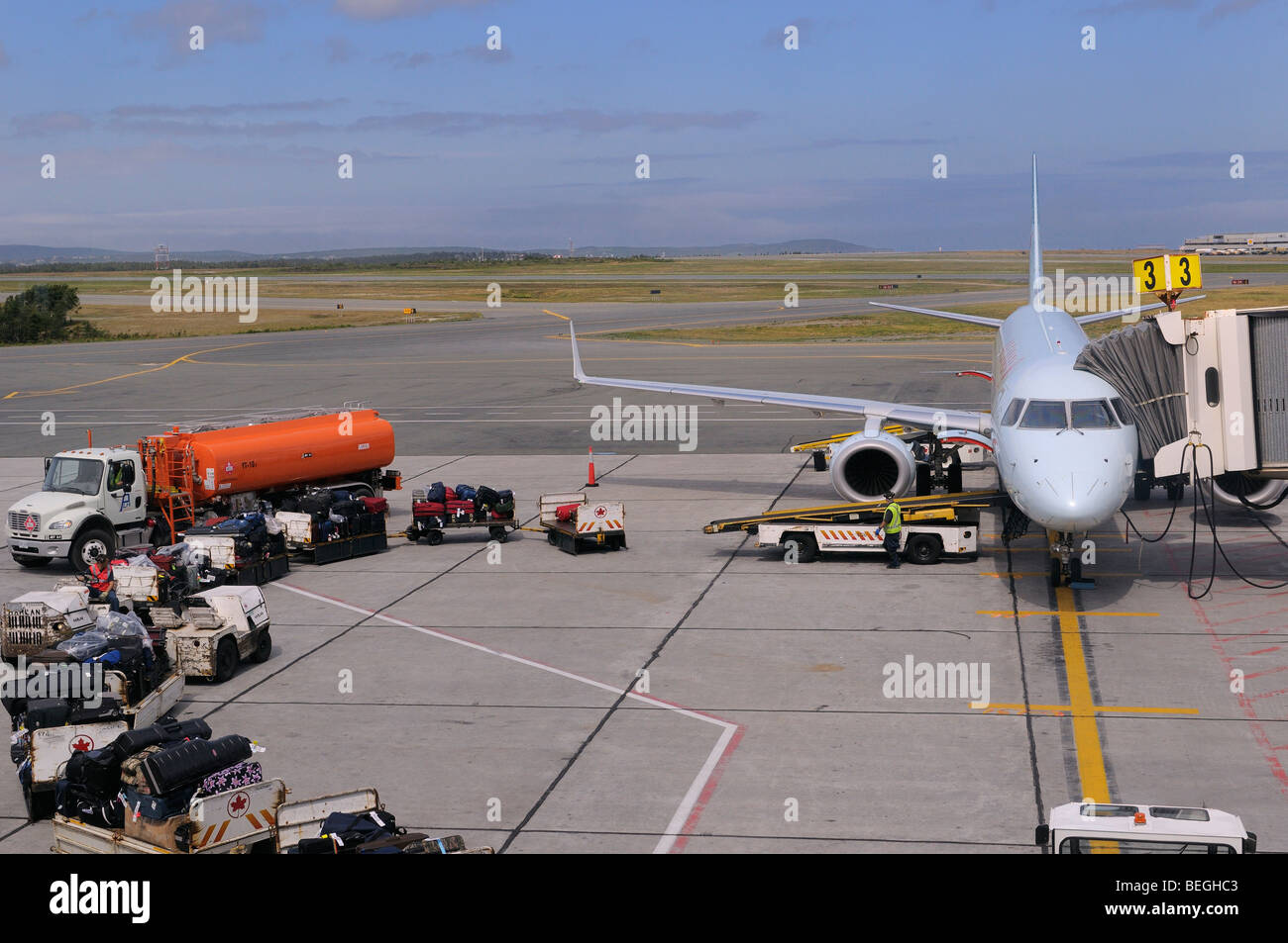 Baggage handlers loading a jet airplane at St. John`s International Airport Newfoundland Stock Photo